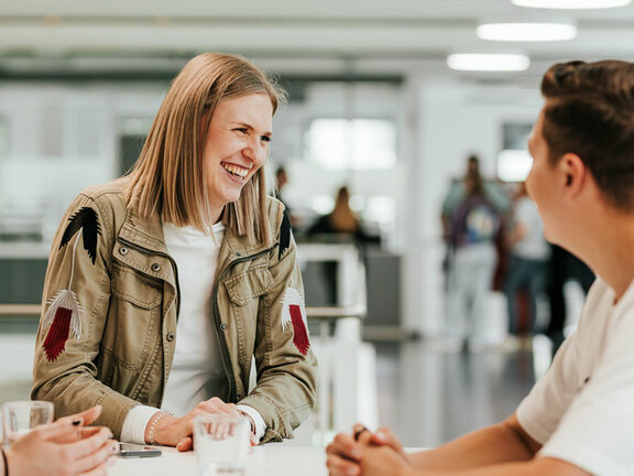 Nahaufnahme einer jungen Frau, welche herzlich lacht.