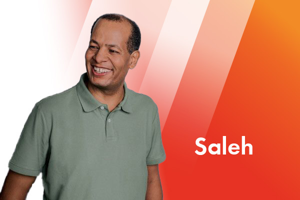 Ein Portrait eines lachenden Mannes, der nach links schaut und ein grünes Polo-Shirt trägt.